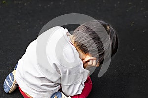 A boy slouches on a dark background. a boy lost in thought