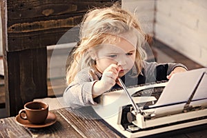 Boy or small kid with typewriter, paper and coffee cup