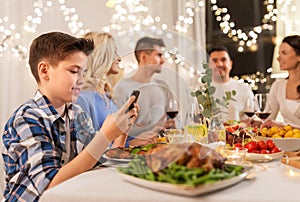 Boy with smartphone at family dinner party