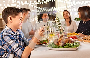 Boy with smartphone at family dinner party