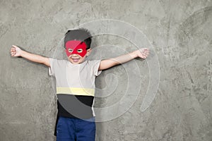 The boy smiling dressed up in superhero costume, he pretends to open arms in the studio for the educational.