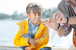 Boy smiling while granddad putting worm on fishing hook