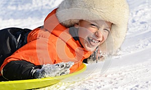 A Boy Smiling Laying on his Sled, Close-up portrait. Winter fun