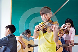 Boy smiling while playing violin in music class