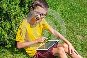 Boy smiling while using tablet in a public park