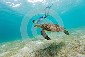 Boy snorkeling with sea turtle