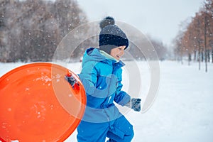 boy in snow in Park. Adorable child having fun in winter park. playing outdoors with snow.
