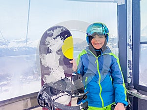 Boy with snowboard in the cabin of a chairlift holding board