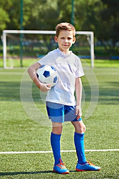 Boy soccer football player with ball on an green grass