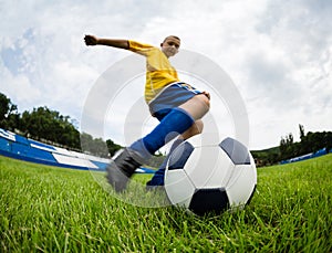 Boy soccer player hits the football ball