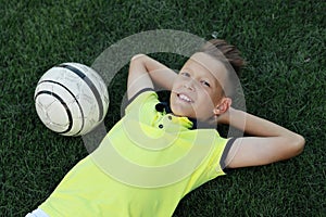 Boy soccer player lies on the soccer field with the ball