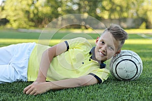 Boy soccer player lies on the soccer field with the ball