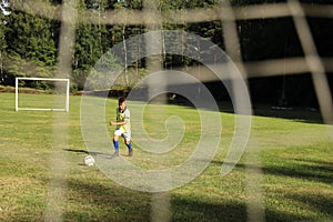 Boy soccer player in a yellow t-shirt on the soccer field plays with a ball