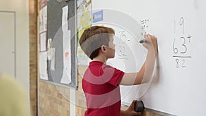 Boy solving math problem at whiteboard