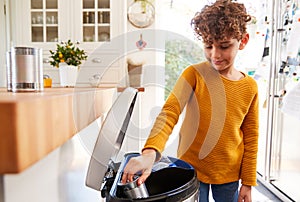 Boy Sorting Recycling Into Kitchen Bin At Home