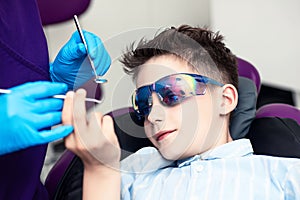 A boy in special glasses in the dentist`s chair. he curiously studies medical instruments in the hands of a doctor
