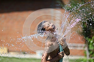 Boy with splash water in hot summer day