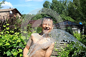 The boy with splash water in very hot summer day outdoors