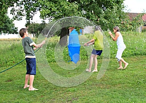 Boy splashing another kids with garden hose