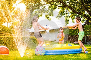 Boy splashing girls with water gun in the garden