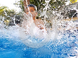 A boy is splashing in a swimming pool