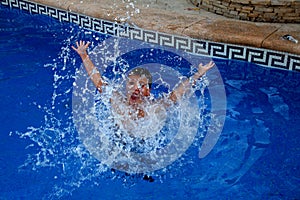 A boy is splashing in a swimming pool