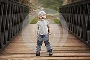 boy in sportswear posing during a trip on a wooden bridge