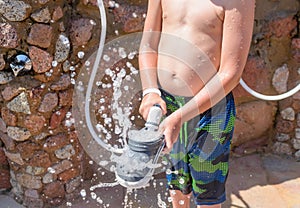 Boy spraying off his shoes with water