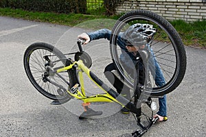 Boy squatting on the floor and checks his bike