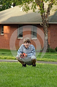 Boy Squatting Holding Football