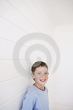 Boy Standing Against Weather Boarded Wall