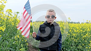 Boy standing with the american flag on the green and yellow field celebrating national independence day. 4th of July