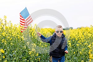 Boy standing with the american flag on the green and yellow field celebrating national independence day. 4th of July concept