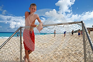 Boy standing at beach goalpost photo