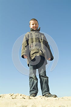 Boy standing at the beach, looking down