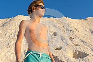 Boy standing on the beach looks into the distance