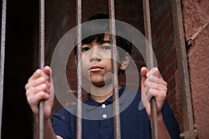 Boy standing behind bars