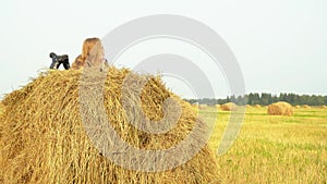Boy standing on field and girl lying on haystack