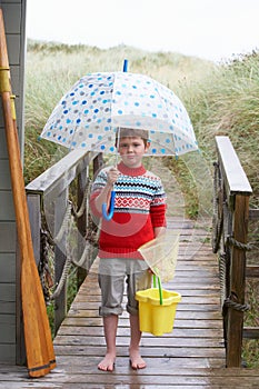 Boy standing on footbridge with umbrella