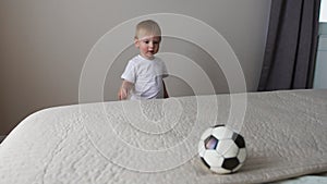 The boy is standing in front of the parents` bed and having fun with their parents