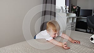 The boy is standing in front of the parents` bed and having fun with their parents