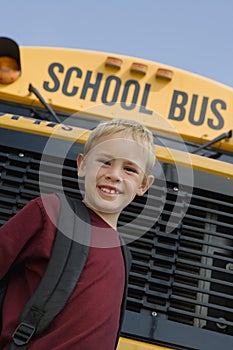 Boy Standing In Front Of School Bus