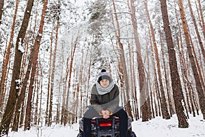 A boy is standing near a quad bike in the middle of the forest