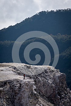 A boy is standing and relaxing on a cliff. Tebing Soni is one of the favorite place to visit on mount Papandayan. Papandayan