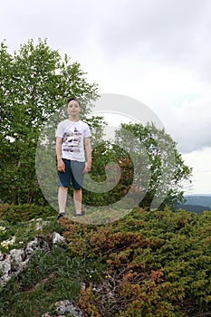 Boy standing on rock on Lago-Naki plateau in summer