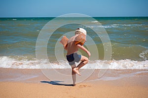 Boy standing on sea coast at surf and looking to water