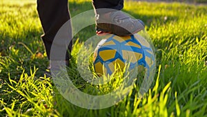 A boy standing on a soccer ball on green grass.