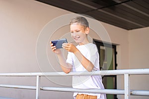 A boy is standing on the street with a phone