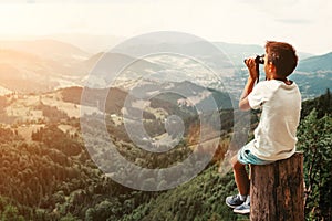 Boy standing on of stump in summer mountains