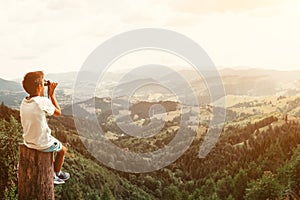 Boy standing on of stump in summer mountains